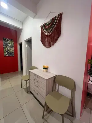 a room with two chairs and a dresser and a red wall at RedHouse Sky Garden Klabang in Ipoh