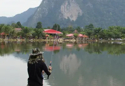 a person in the water holding a fishing rod at Belibis Yard in Kampar