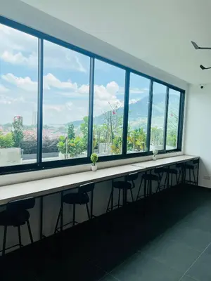 a long table with stools in a room with windows at Lavender Villa Marc Residence Bukit Mertajam in Bukit Mertajam