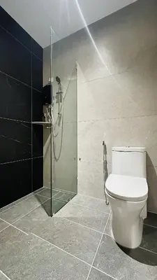 a bathroom with a toilet and a glass shower at Legend Inn Sungai Petani in Sungai Petani