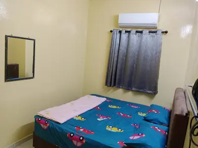 a bedroom with a bed with a blue comforter and a mirror at Krishna Villa in Simpang