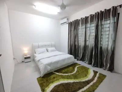 a bedroom with a white bed and a green rug at Lilly Grove Homestay in Kampong Ayer Melintas Besar