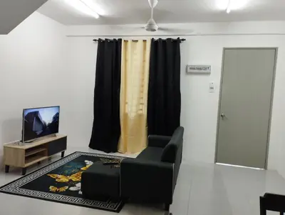 a living room with a black chair and a television at Lilly Grove Homestay in Kampong Ayer Melintas Besar
