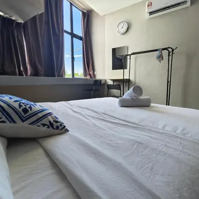 a white bed with a pillow and a clock on the wall at Wayton Cottage in George Town