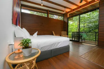 a bedroom with a bed and a balcony with a table at The HIJAU Camp & Cabin in Gopeng