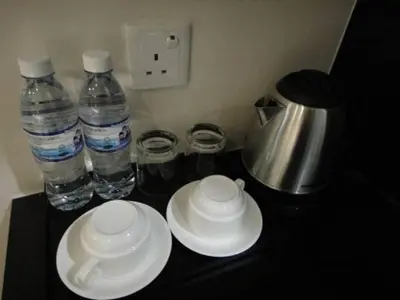 a counter with three bottles of water and white plates at Galaxy Hotel SIMPANG AMPAT in Simpang Ampat