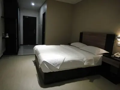 a bedroom with a large white bed and a telephone at Galaxy Hotel SIMPANG AMPAT in Simpang Ampat