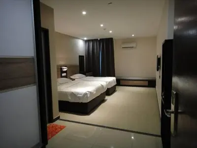 a bedroom with two beds and a door to a room at Galaxy Hotel SIMPANG AMPAT in Simpang Ampat