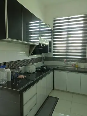 a kitchen with white cabinets and black counter tops at D'Sawah Homestay in Kampong Gunong Semanggol