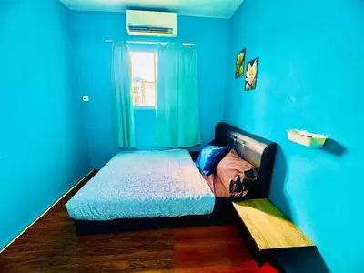 a blue bedroom with a bed in a room with a window at 2br bayan lepas 1car park Malaysian guest only in Bayan Lepas