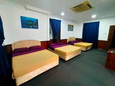 a room with two beds and blue curtains at Capital O 91118 Chalet Seri Idaman in Kampong Batu Maung