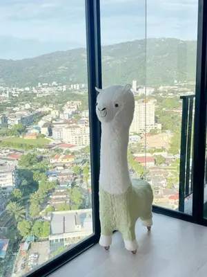 a stuffed sheep standing in front of a window at The Floral Retreat N3w Cozy High floor Beacon Executive Suite in George Town