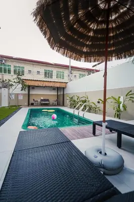 a swimming pool with an umbrella and a table at Dyra Homestay in Lumut in Lumut