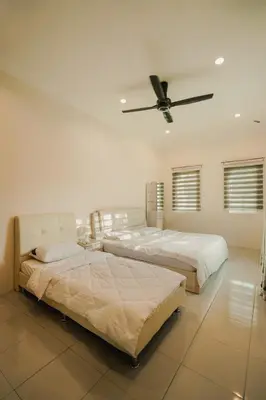 two beds in a bedroom with a ceiling fan at Dyra Homestay in Lumut in Lumut