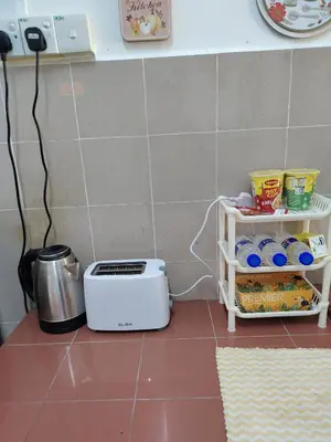 a kitchen with a toaster and a shelf with food at Suria Permai19 Homestay in Taiping