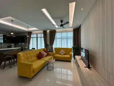 a living room with two yellow couches and a television at Luxury 5BR stay walk to beach & Night market fun in Batu Ferringhi