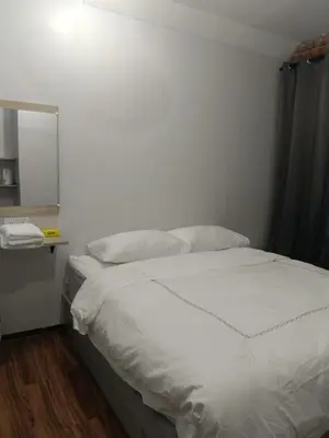 a white bed in a room with a mirror at Olly de Home Ent in Batu Gajah