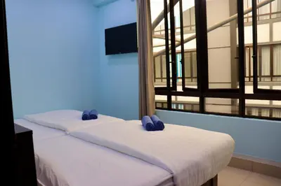 two beds in a room with blue walls and windows at Hotel Aaraa in Brinchang