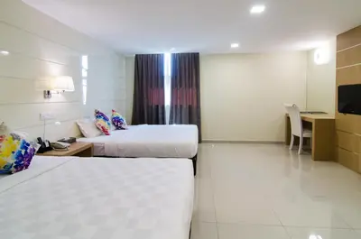 a hotel room with two beds and a desk at Mornington Hotel Sitiawan in Sitiawan