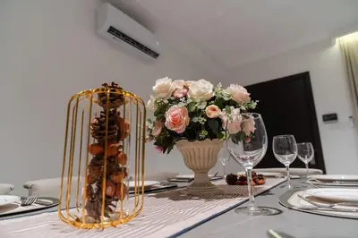 a table with a vase of flowers on a table with glasses at Georgetown Italian-Style Jacuzzi KTV 5BR 18pax G in George Town