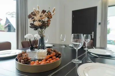 a table with a bowl of flowers and wine glasses at Georgetown Modern Brown-Colored KTV 5BR 18pax H in George Town