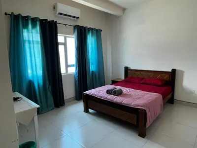 a bedroom with a bed with red sheets and blue curtains at Homestay Adyana in Raub