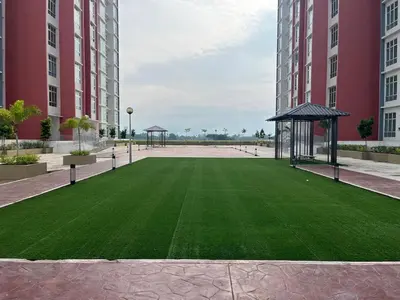 a green lawn in a courtyard between two tall buildings at The Anderson Ipoh AA4 7pax, Smart TV & Wi-Fi in Ipoh
