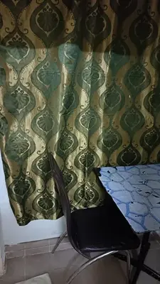 a chair sitting in front of a wall with a curtain at Cool view hotel in Tanah Rata