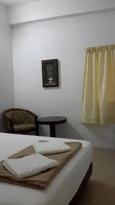 a room with a bed with a table and a window at Rasa Motel in Batu Ferringhi