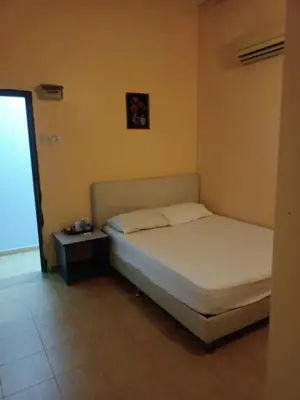 a bedroom with a white bed and a night stand at Wonderful Motel in Taiping