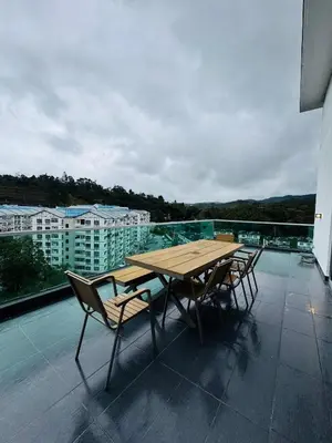 a wooden table and chairs on a balcony at AYAAN PENTHOUSE at QUINTET 5 BED ROOM & ROOFTOP SKY DINING in Tanah Rata