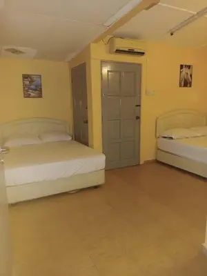 two beds in a room with yellow walls at Wonderful Motel in Taiping