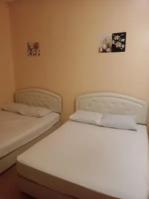 two twin beds in a room with two pictures on the wall at Wonderful Motel in Taiping