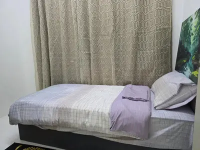 a small bed in a bedroom with a curtain at Aqimi Homestay in Seri Iskandar