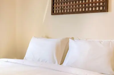 a bed with white pillows in a room at The Sun by Stellar ALV in Bayan Lepas