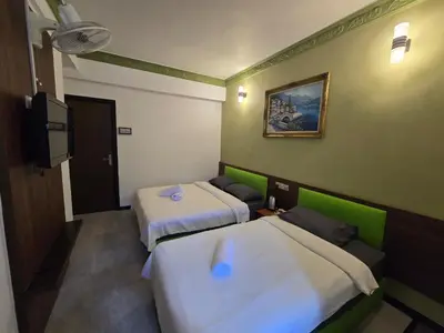 a room with two beds and a flat screen tv at D GAYA HOTEL Cameron Highlands in Tanah Rata