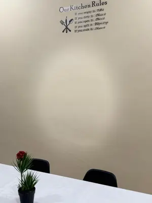 a table with chairs and a sign on a wall at Utaqha Ventures Homestay in Seri Manjung