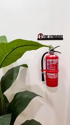 a fire extinguisher hanging on a wall next to a plant at Dahlia Kulim Pool Homestay in Kulim