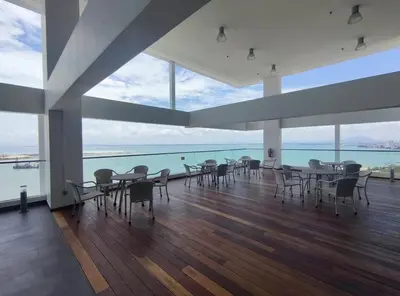 a dining room with tables and chairs and the ocean at Cozy Seaview Duplex Apartment at Sunrise Gurney in George Town