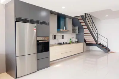 a kitchen with a stainless steel refrigerator and a staircase at Cozy Seaview Duplex Apartment at Sunrise Gurney in George Town