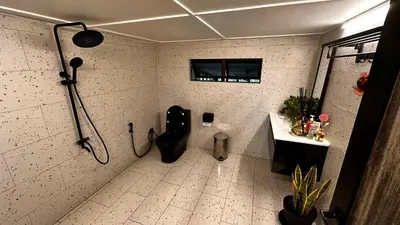 a bathroom with a shower and a toilet in a room at Charming Nature Kampung Home for Family Getaways in Benta
