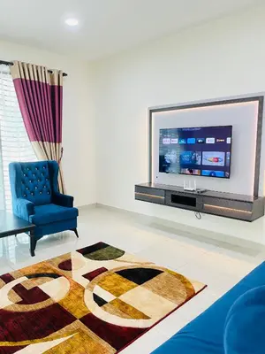 a living room with a tv and a blue chair at Sofea Homestay Ipoh V2 in Ipoh