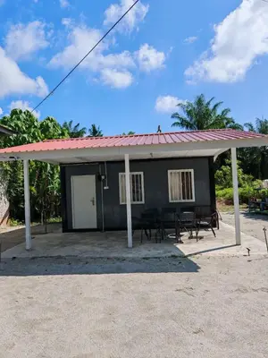 a small black house with a red roof at STUDIO HOMESTAY Arjuna in Pantai Remis