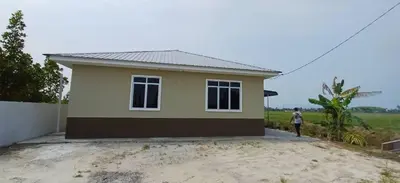 a man standing in front of a small house at d'esaku homestay in Penaga