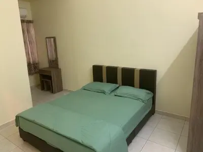 a bedroom with a bed with a green comforter at TD Homestay in Ipoh
