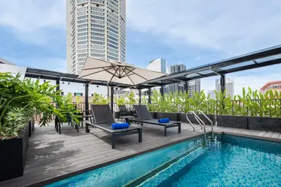 a rooftop deck with a pool and chairs and a umbrella at Citadines Connect Bertam Georgetown Penang in George Town