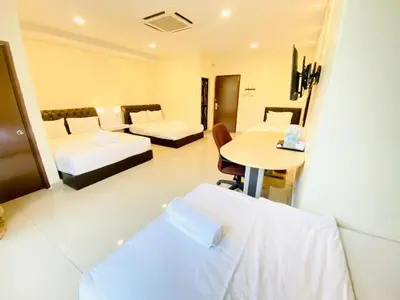 a hotel room with two beds and a table at Sunsega Hotel in Perai