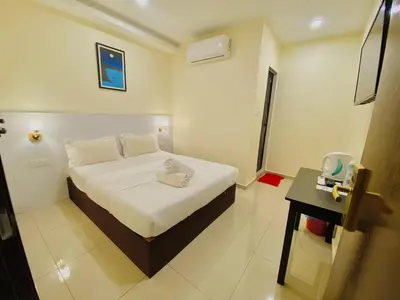 a white bedroom with a bed and a table at Sunsega Hotel in Perai