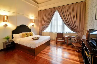 a bedroom with a bed and a desk and a television at Sarang Paloh Heritage Stay in Ipoh