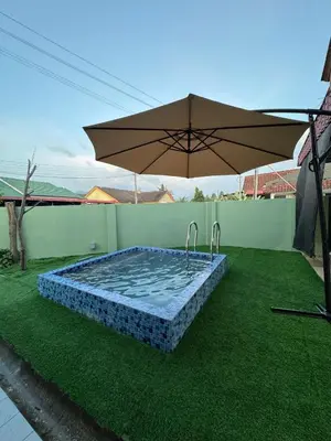 a swimming pool with an umbrella on the grass at Casa de' Sara Pool Homestay Ipoh in Ipoh